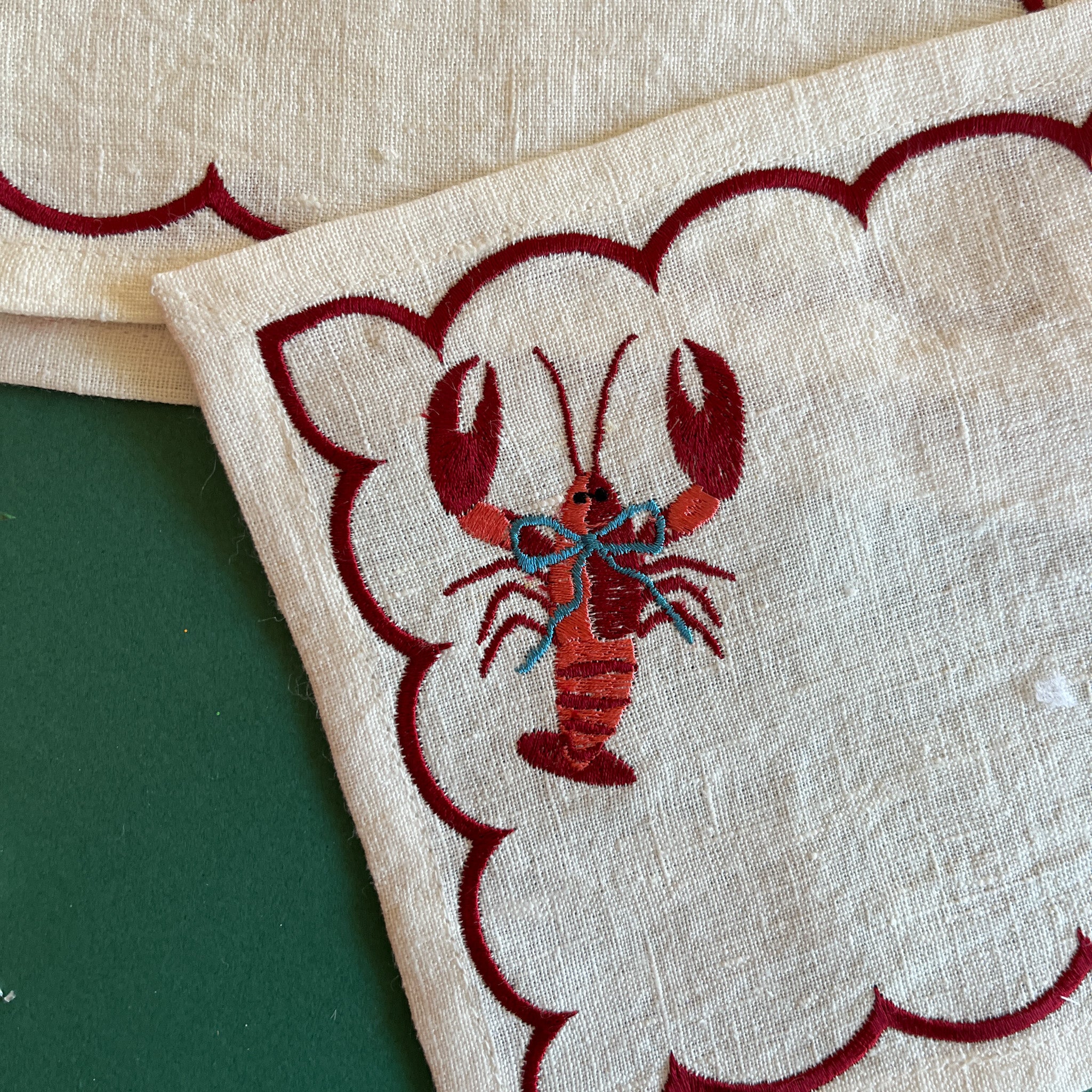 Detail of embroidered blue blow lobster on a linen cocktail napkin