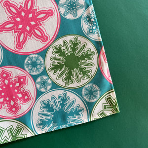 Detail view of snowflakes in pink, green and turquoise on the Snowflake Wonderland Christmas cloth table runner