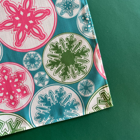 Detail view of snowflakes in pink, green and turquoise on the Snowflake Wonderland Christmas cloth table runner