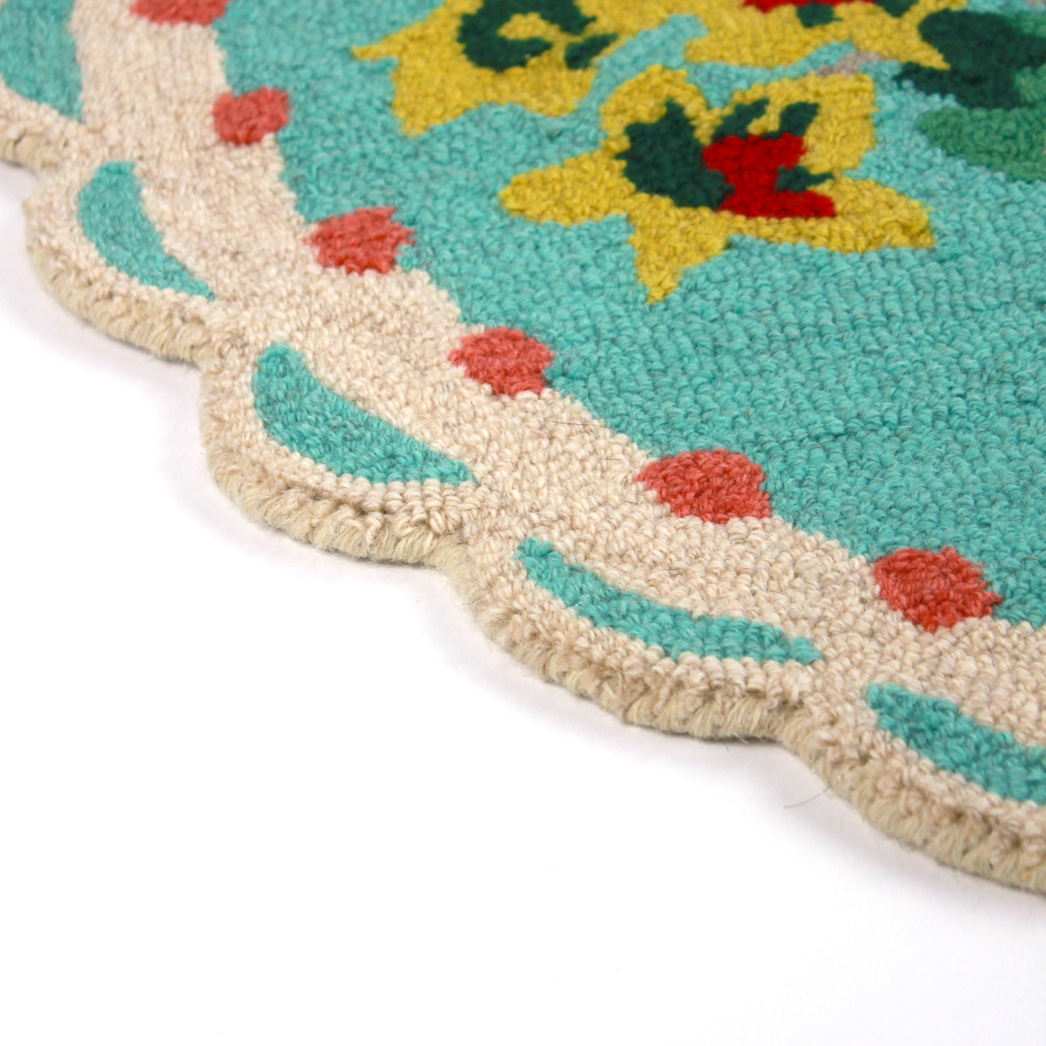 close up detail of A blue oval rug with strawberry and flower motifs and a scalloped border