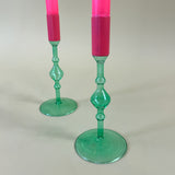 Detail view of two green colored glass candle holders with pink tops