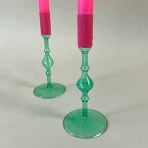 Detail view of two green colored glass candle holders with pink tops
