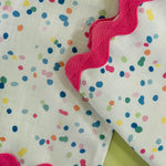 close up of a confetti multicolor fabric napkin with ric rac trim from Madcap Cottage on a light green background.