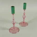 Pair pink glass candleolders with green tops on a light green background