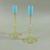 two yellow colored glass candle holders with blue tops