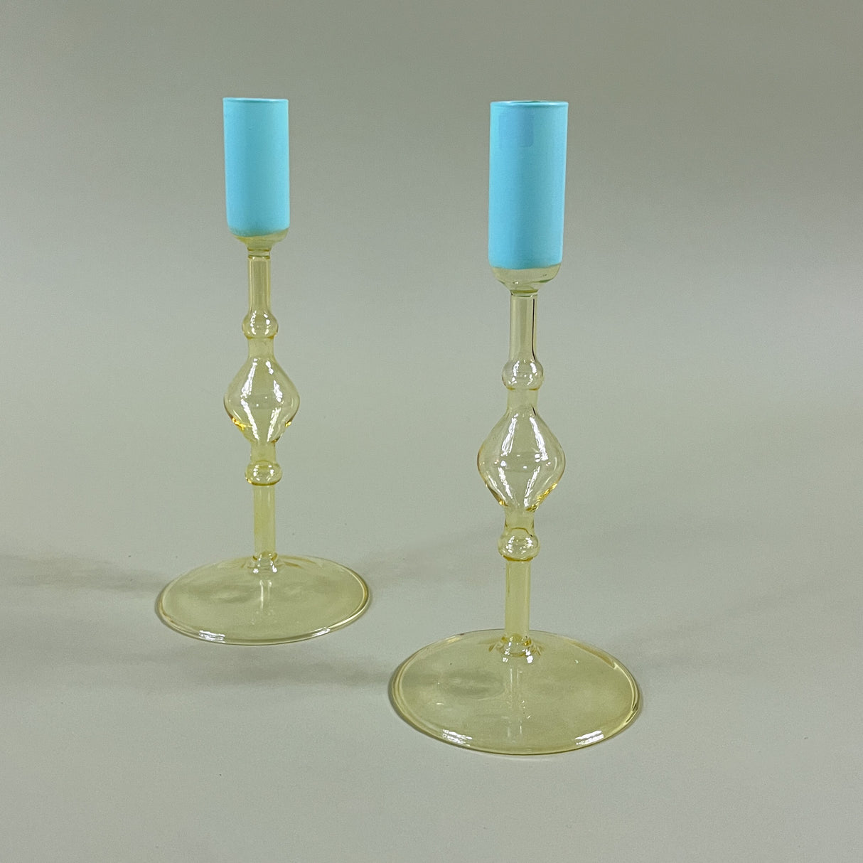 two yellow colored glass candle holders with blue tops