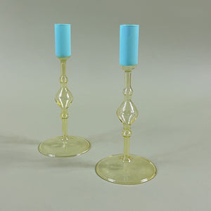 two yellow colored glass candle holders with blue tops