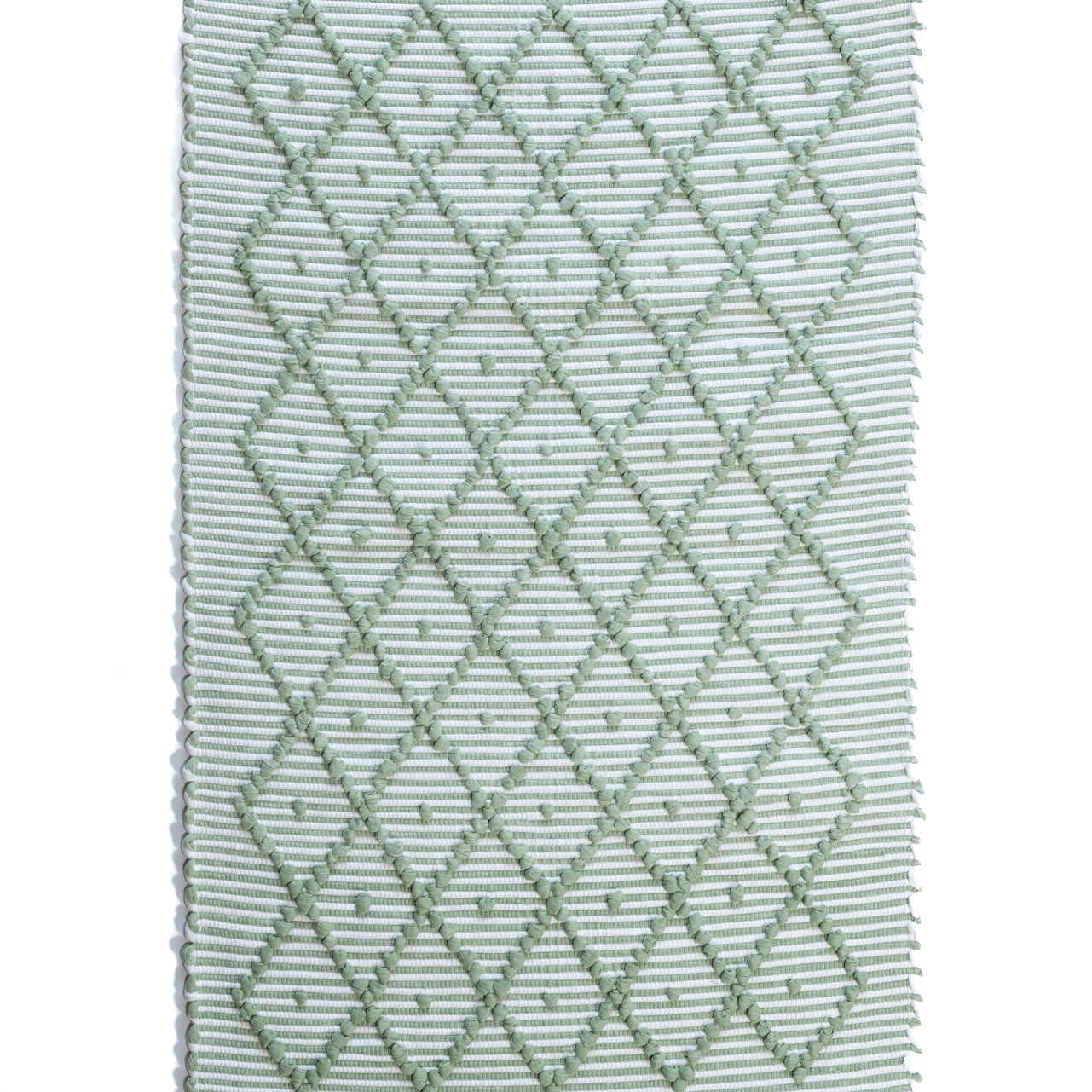 A Madcap Cottage green accent rug with a diamond pattern on the front 