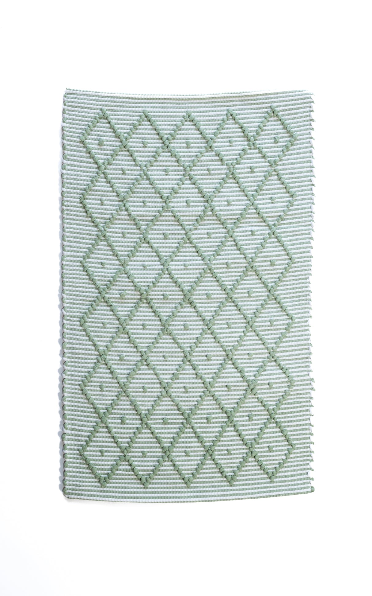 A Madcap Cottage green accent rug with a diamond pattern on the front 