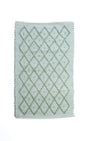A Madcap Cottage green accent rug with a diamond pattern on the front 