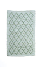 A Madcap Cottage green accent rug with a diamond pattern on the front 