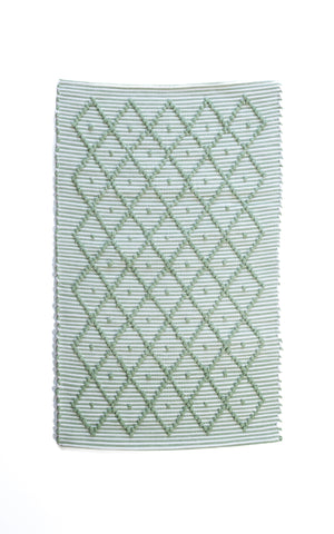 A Madcap Cottage green accent rug with a diamond pattern on the front 