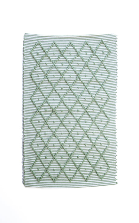 A Madcap Cottage green accent rug with a diamond pattern on the front 