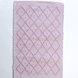 A madcap cottage cotton pink accent rug with a diamond pattern on the front 
