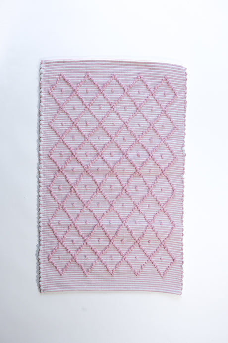 A madcap cottage cotton pink accent rug with a diamond pattern on the front 