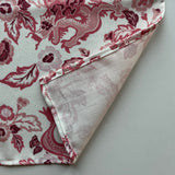 Close up of the hem of the East of the Sun chinoiserie cloth dinner napkin shown in red