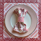 Layered placemats in reds and pinks with a light pink china plate on top, holding our East of the Sun chinoiserie cloth dinner napkin