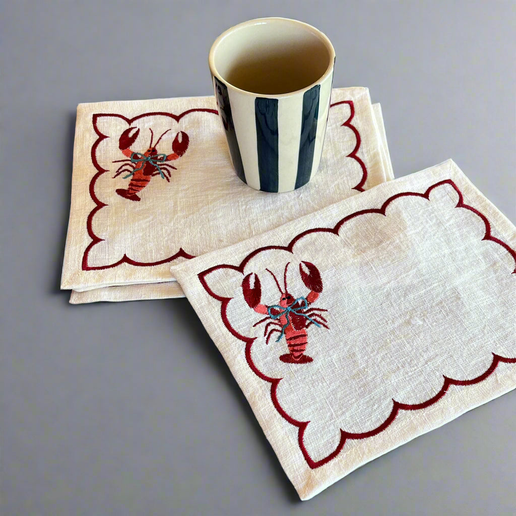 Embroidered blue bow lobster linen cocktail napkins with a blue striped cup