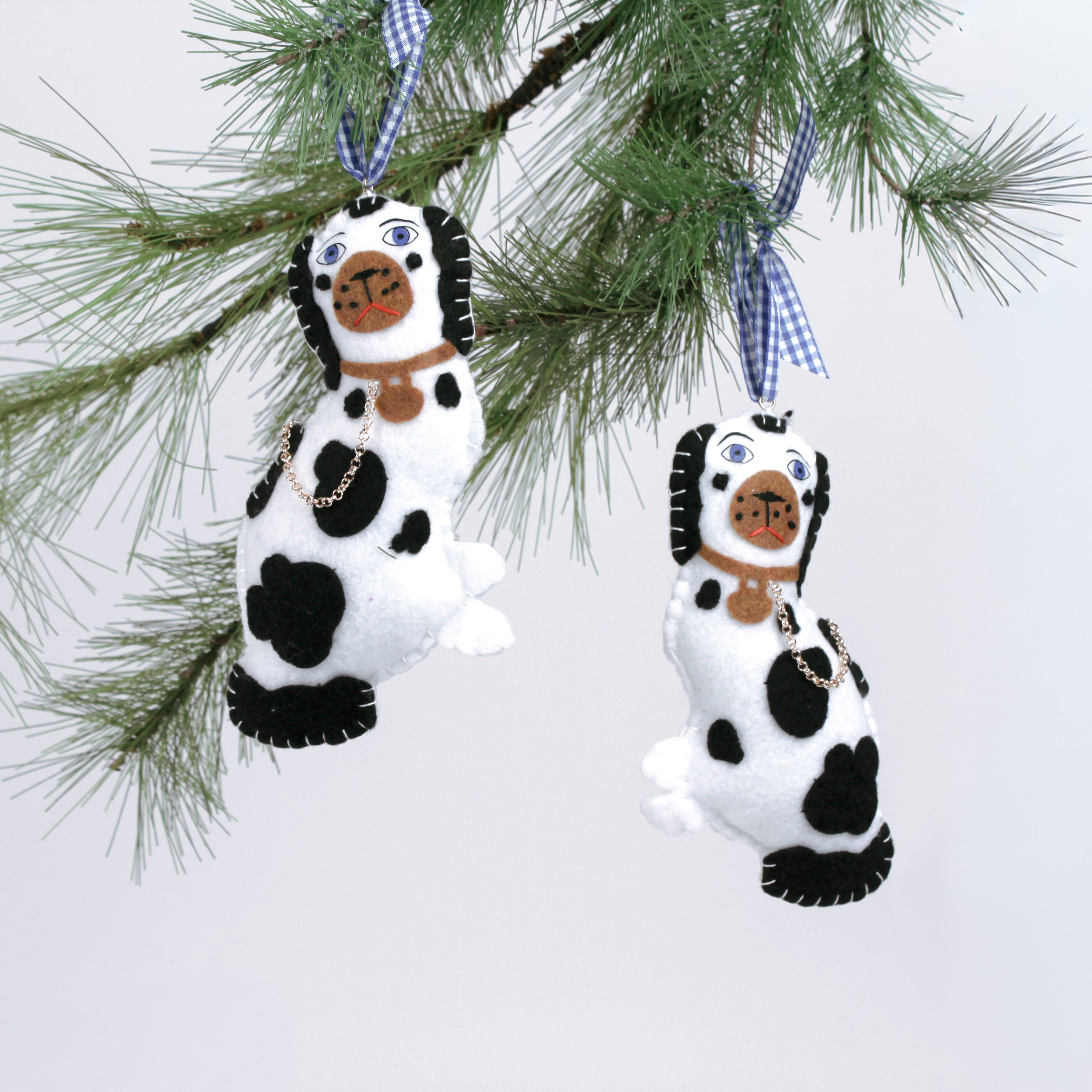 Two black and white staffodshire dog felt christmas ornaments against a white background.