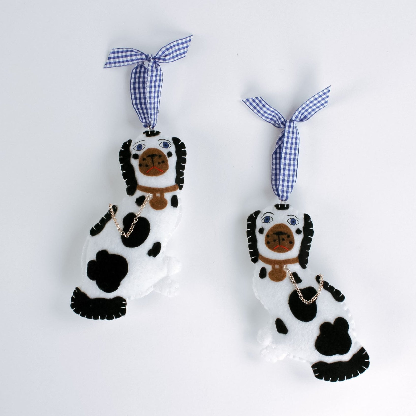 Two black and white staffodshire dog felt christmas ornaments against a white background.