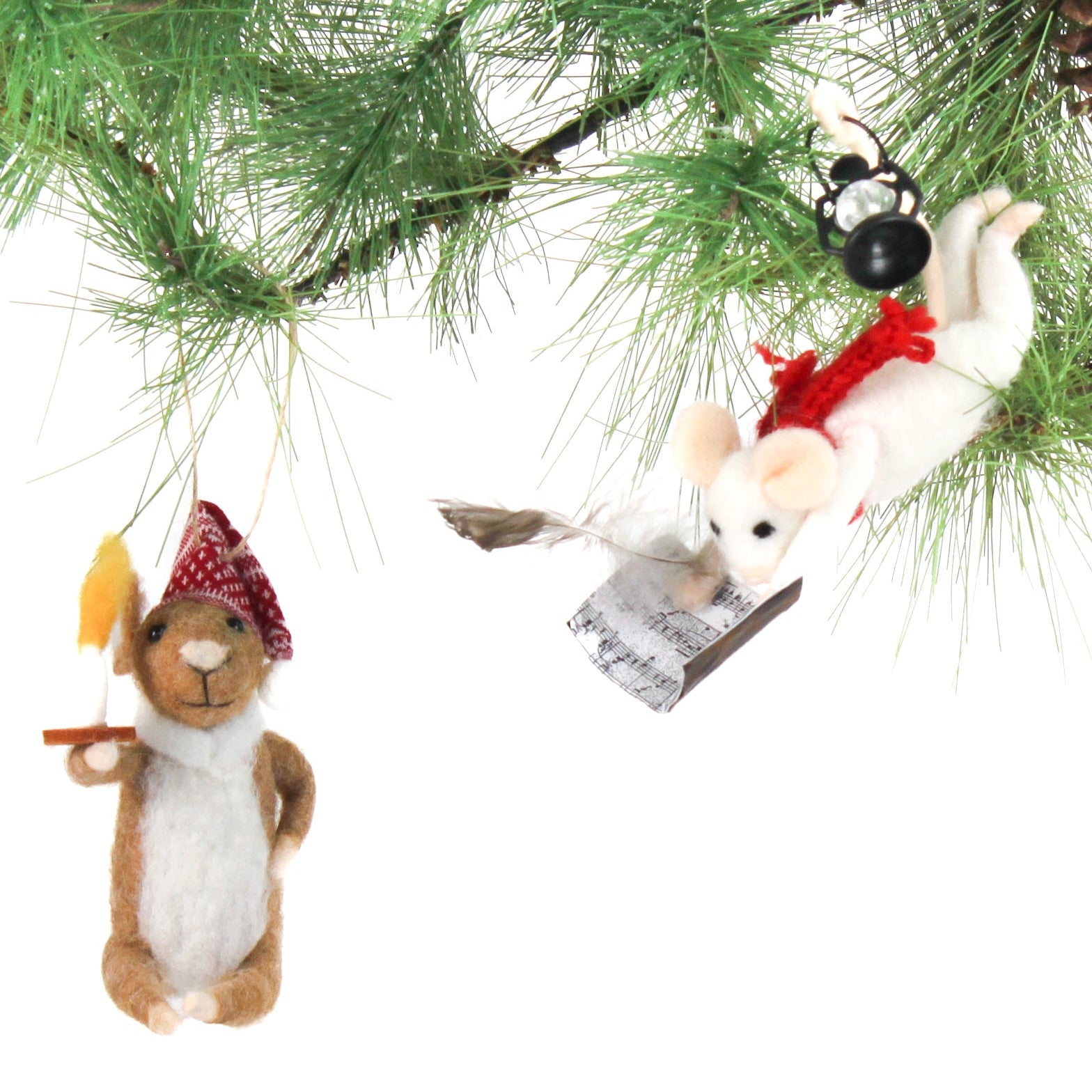 Two felt mouse ornaments hang from pine branches—one wearing a red nightcap and holding a candle, and the other flying with a feather pen, a red ribbon, a book, and a lantern.