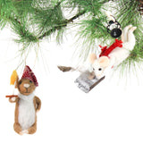 Two felt mouse ornaments hang from pine branches—one wearing a red nightcap and holding a candle, and the other flying with a feather pen, a red ribbon, a book, and a lantern.