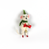 A felt mouse ornament wearing a green scarf and hat holds a red bow with a small gold bell hanging from it.
