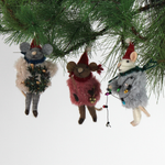 Three festive felt mouse ornaments dressed in fuzzy holiday outfits and Santa hats, holding Christmas decorations like string lights, a wreath, and a gold bell.