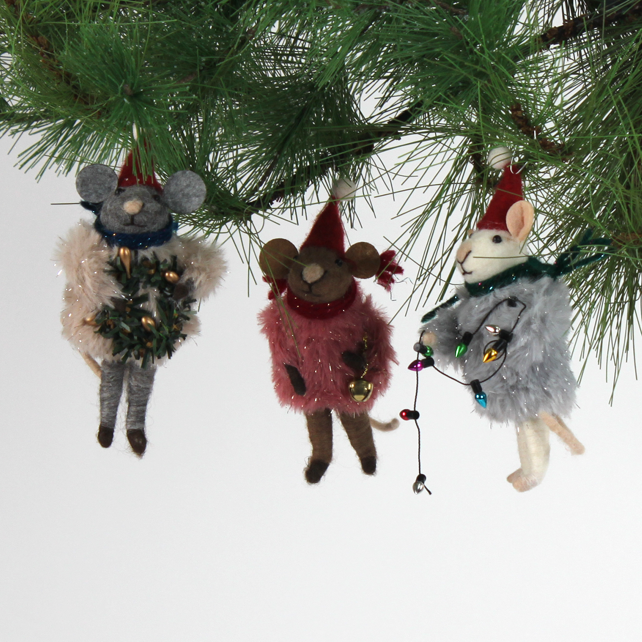 Three festive felt mouse ornaments dressed in fuzzy holiday outfits and Santa hats, holding Christmas decorations like string lights, a wreath, and a gold bell.