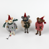 Three festive felt mouse ornaments dressed in fuzzy holiday outfits and Santa hats, holding Christmas decorations like string lights, a wreath, and a gold bell.
