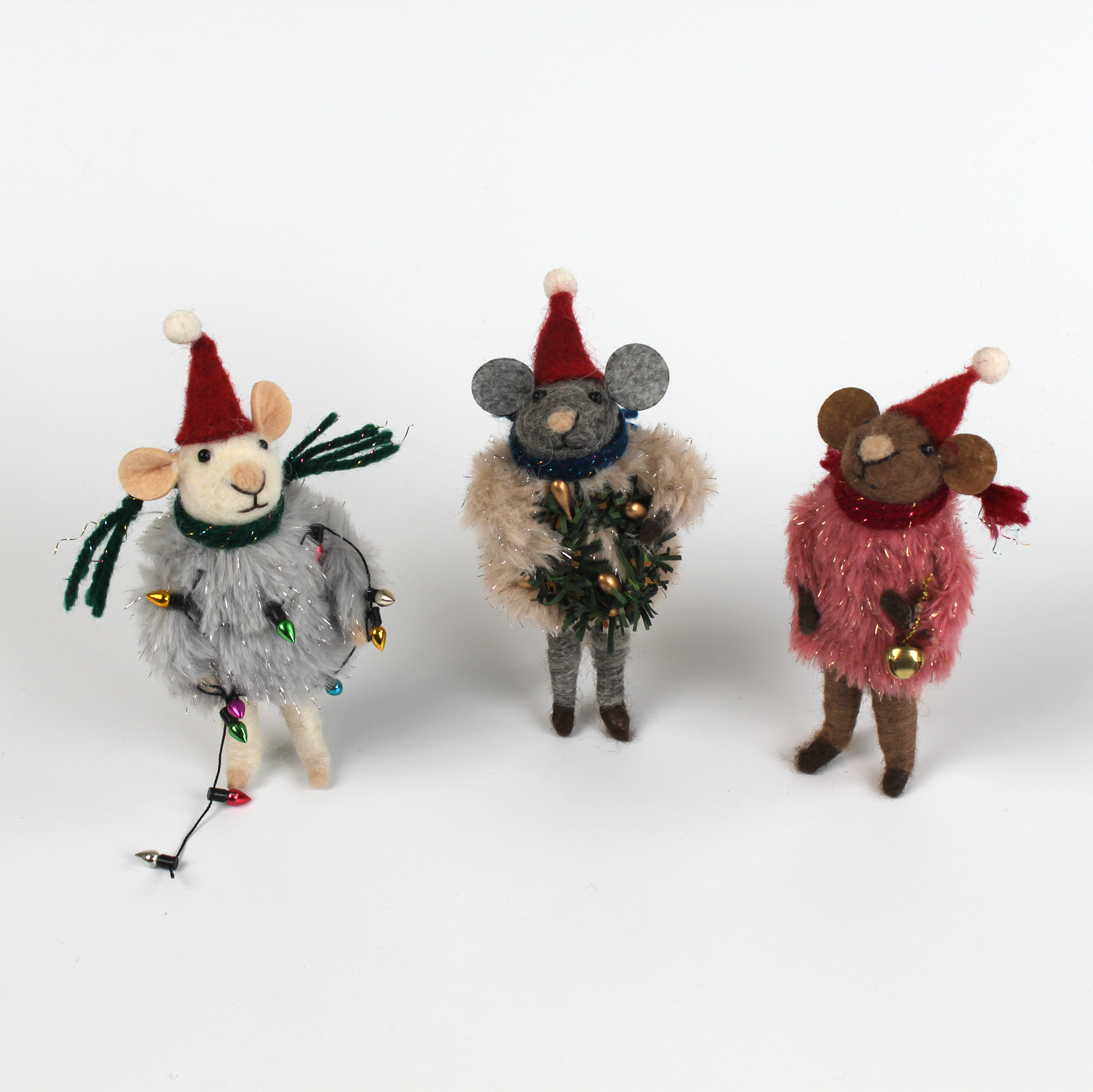 Three festive felt mouse ornaments dressed in fuzzy holiday outfits and Santa hats, holding Christmas decorations like string lights, a wreath, and a gold bell.
