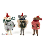 Three festive felt mouse ornaments dressed in fuzzy holiday outfits and Santa hats, holding Christmas decorations like string lights, a wreath, and a gold bell.