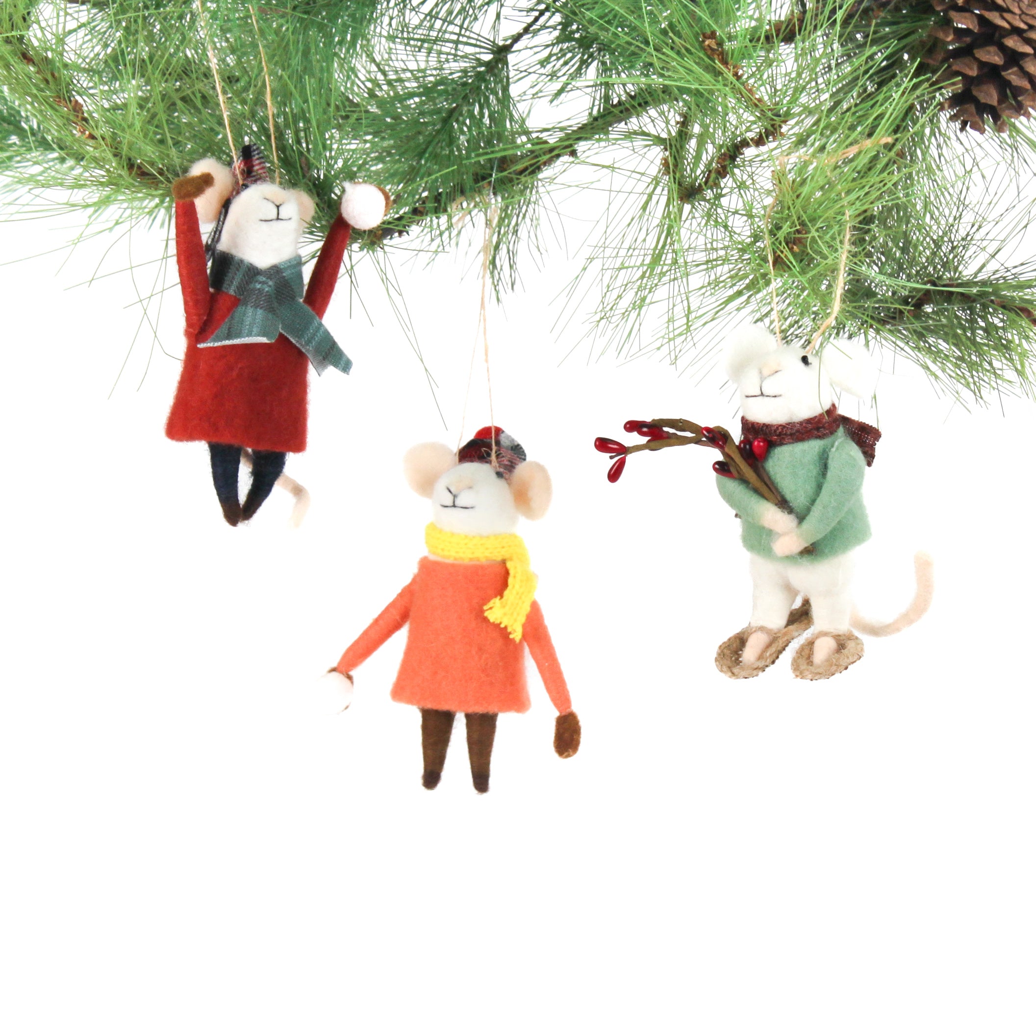 Three felt mouse ornaments dressed for winter—one in a red coat and plaid hat tossing a snowball, one in an orange coat with a yellow scarf holding a snowball, and one in a green sweater holding red berries—shown hanging on a tree