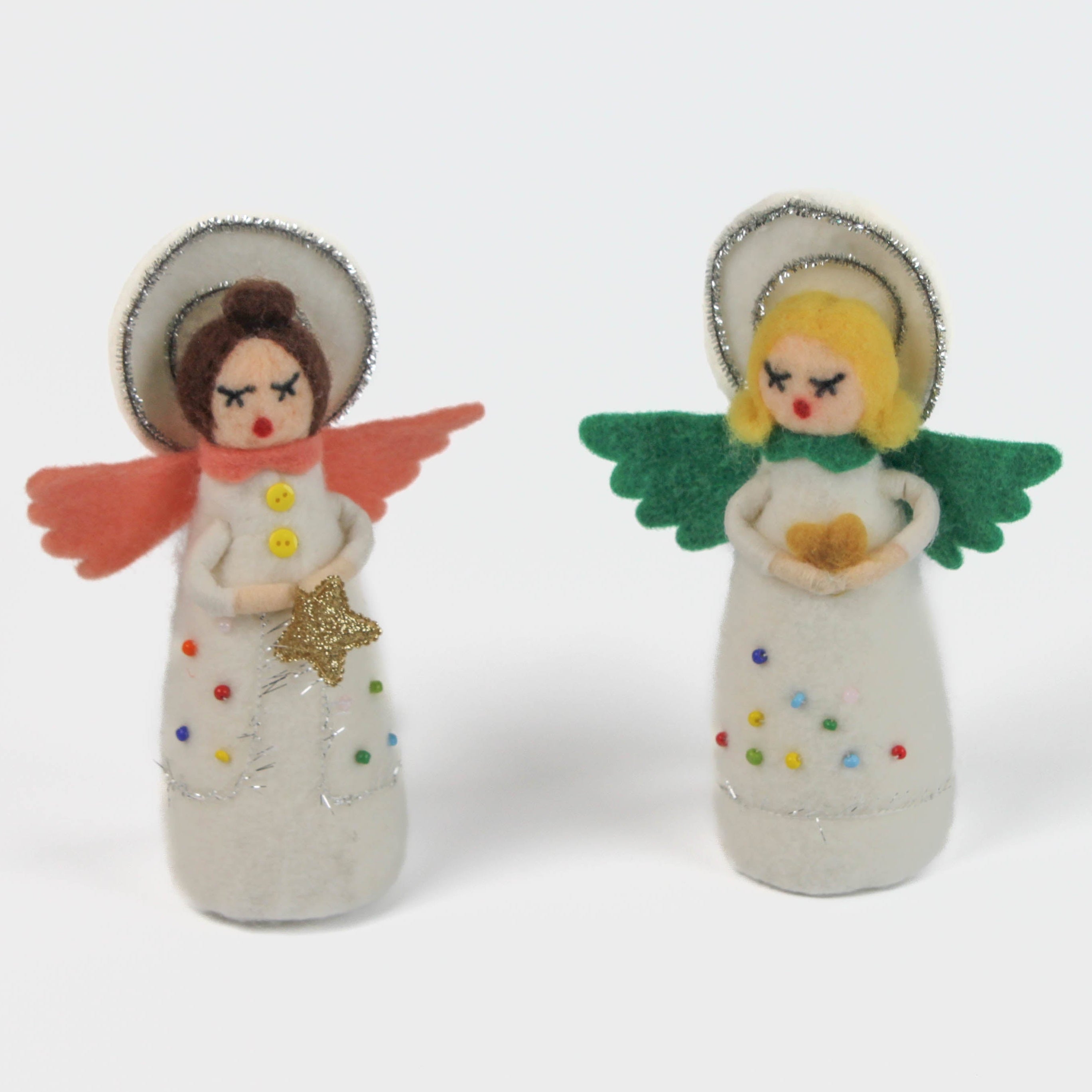 Two angel christmas table decoration made from felt with colorful clothing and wings on a white background