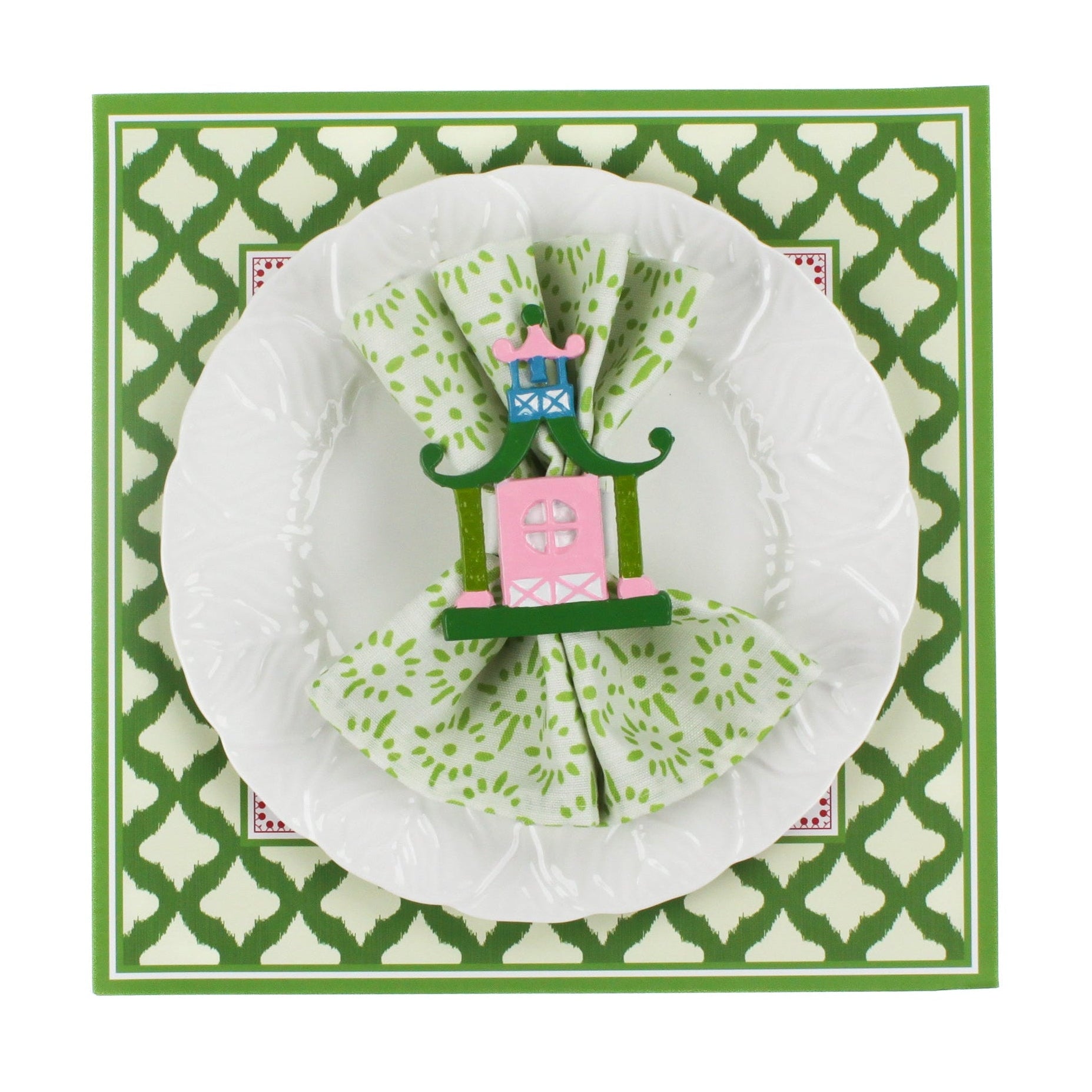 Festive pagoda square paper placemats in a white background. A white plate is placed on top of it with a cloth and a pagoda napkin ring