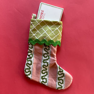 A green and pink Christmas stocking stuffed with a notepad