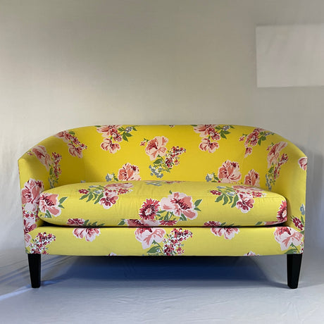 Yellow floral loveseat with large pink flowers and green leaves on  yellow background