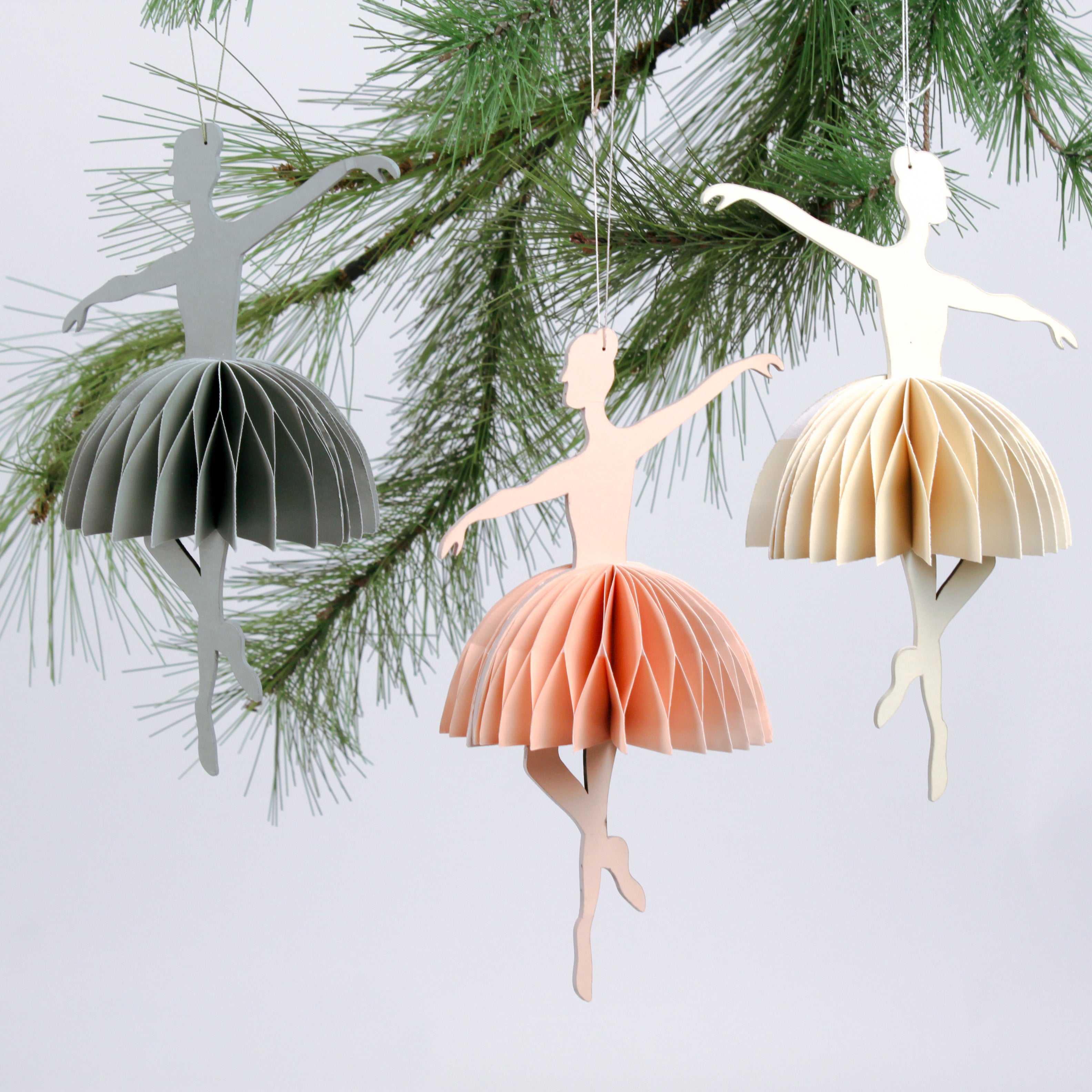 Three ballerina christmas ornaments hanging from a tree branch.
