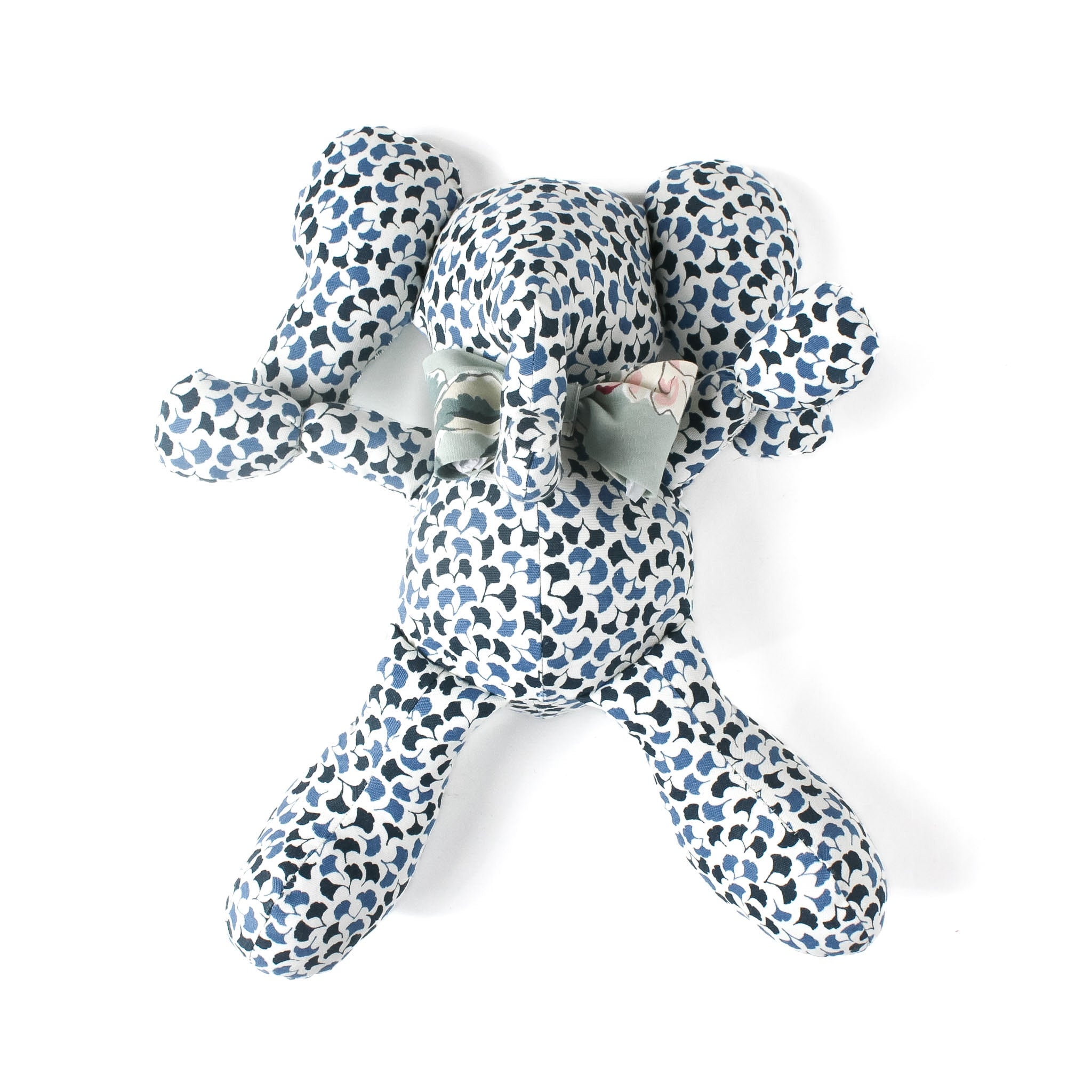 Blue and white patterned stuffed elephant toy with a green bow.