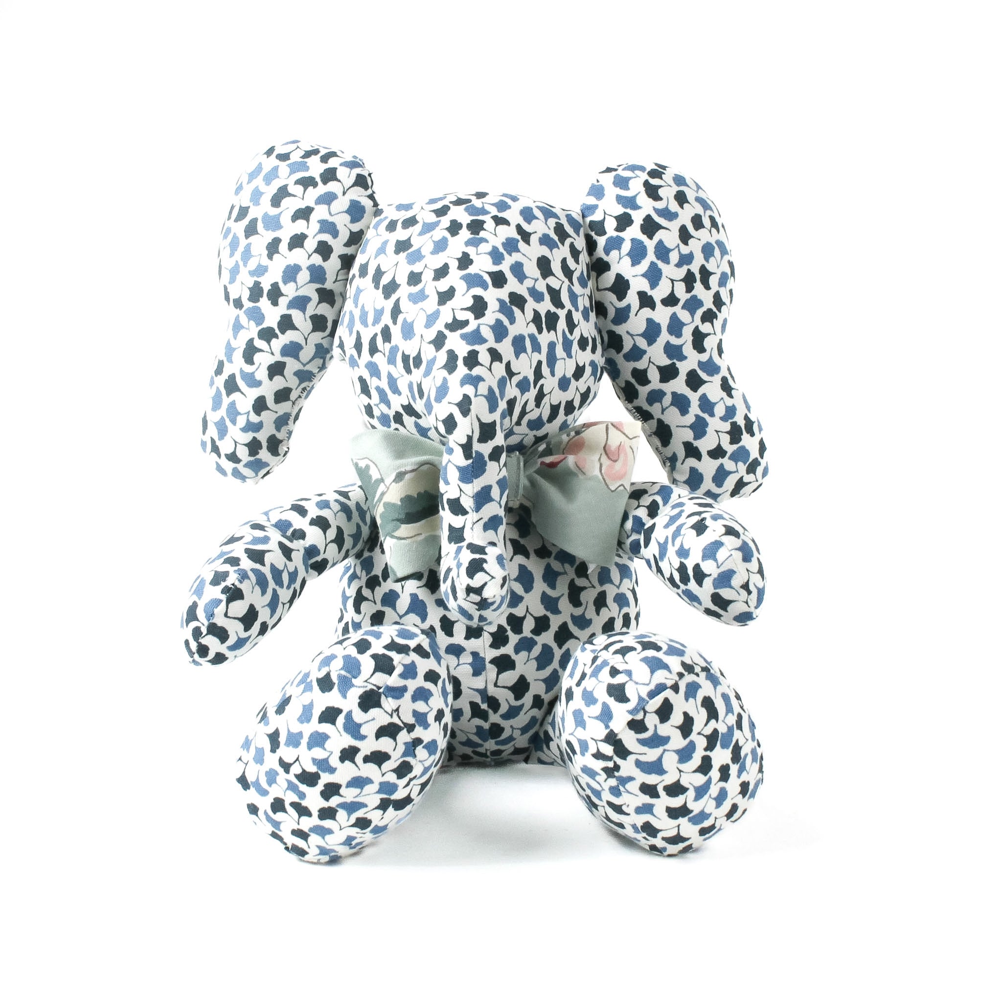 Blue and white patterned stuffed elephant toy with a green bow.