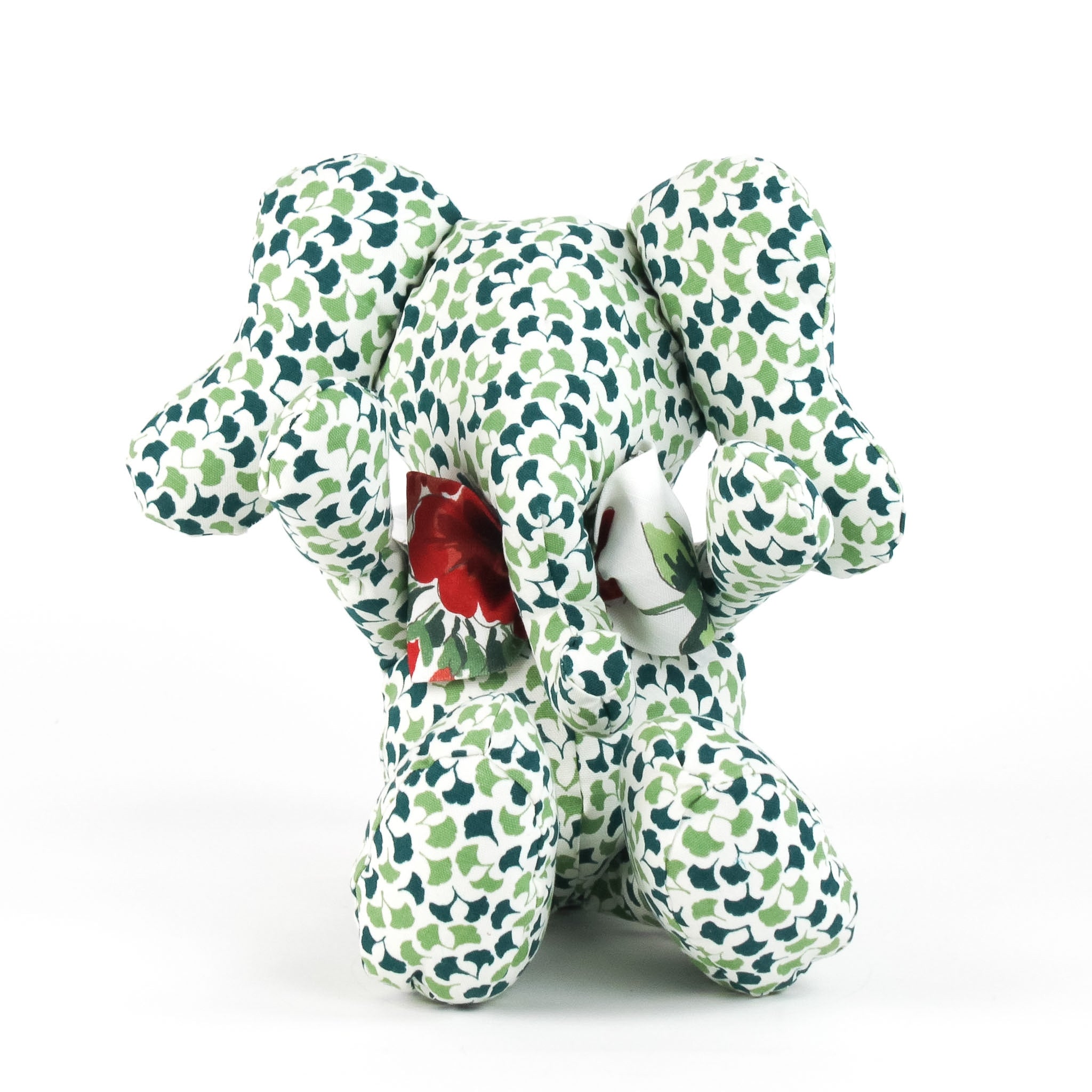 Green and white patterned stuffed elephant toy with a red bow.