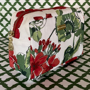 Front 3/4 view of Cottage Grove Geranium is a floral toiletries bag with a red, green, and white color scheme, featuring a geranium design.