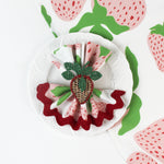 Strawberry-print cloth napkin styled on a white plate with a woven strawberry napkin ring.