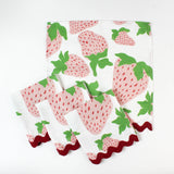Set of cloth napkins with pink strawberry print and red scalloped trim.