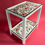 a red, green and white side table painted with red geraniums from madcap cottage