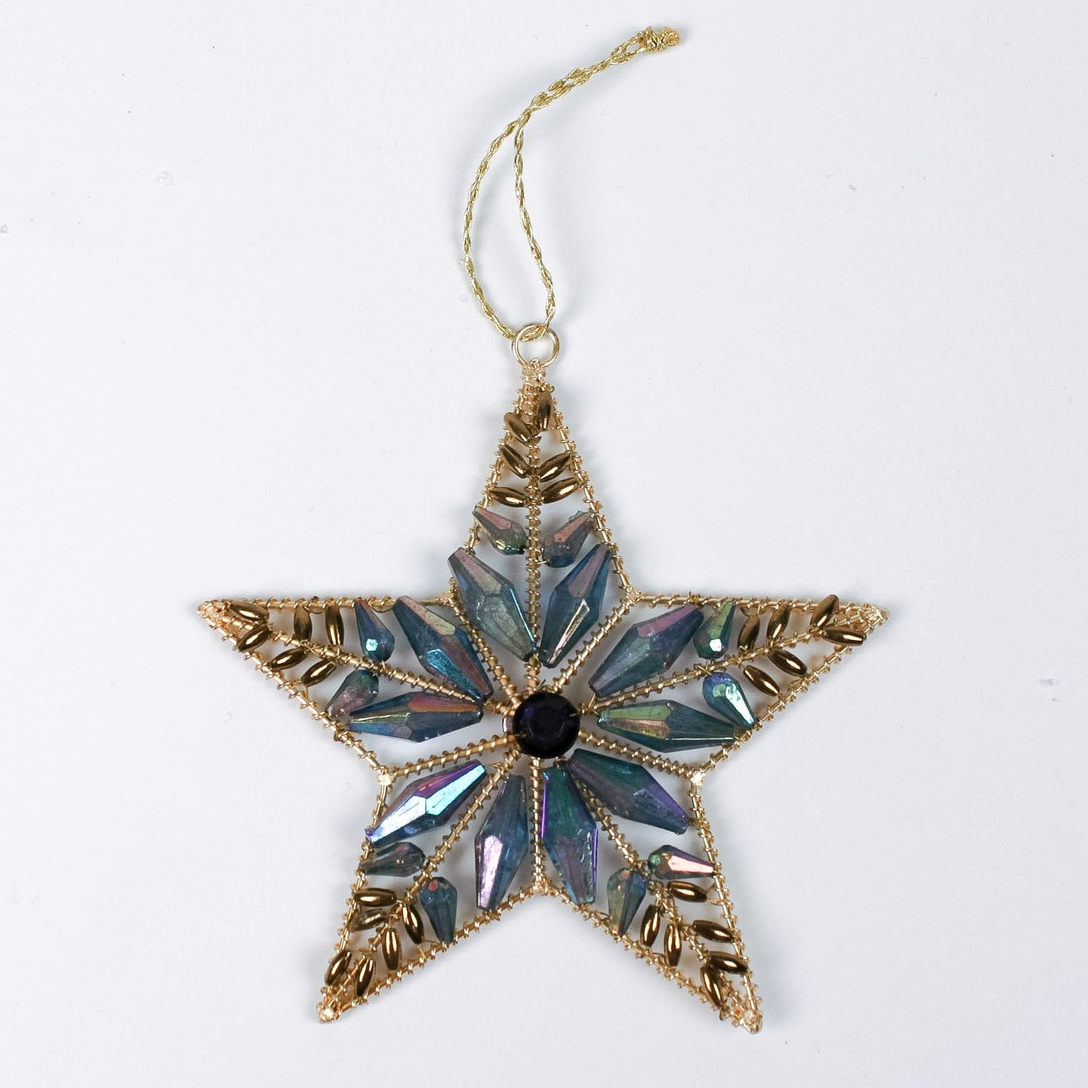 Gilt metal star shaped Christmas ornament decorated with blue and iridescent crystal accents and a dark gemstone at the center, displayed against a white background.