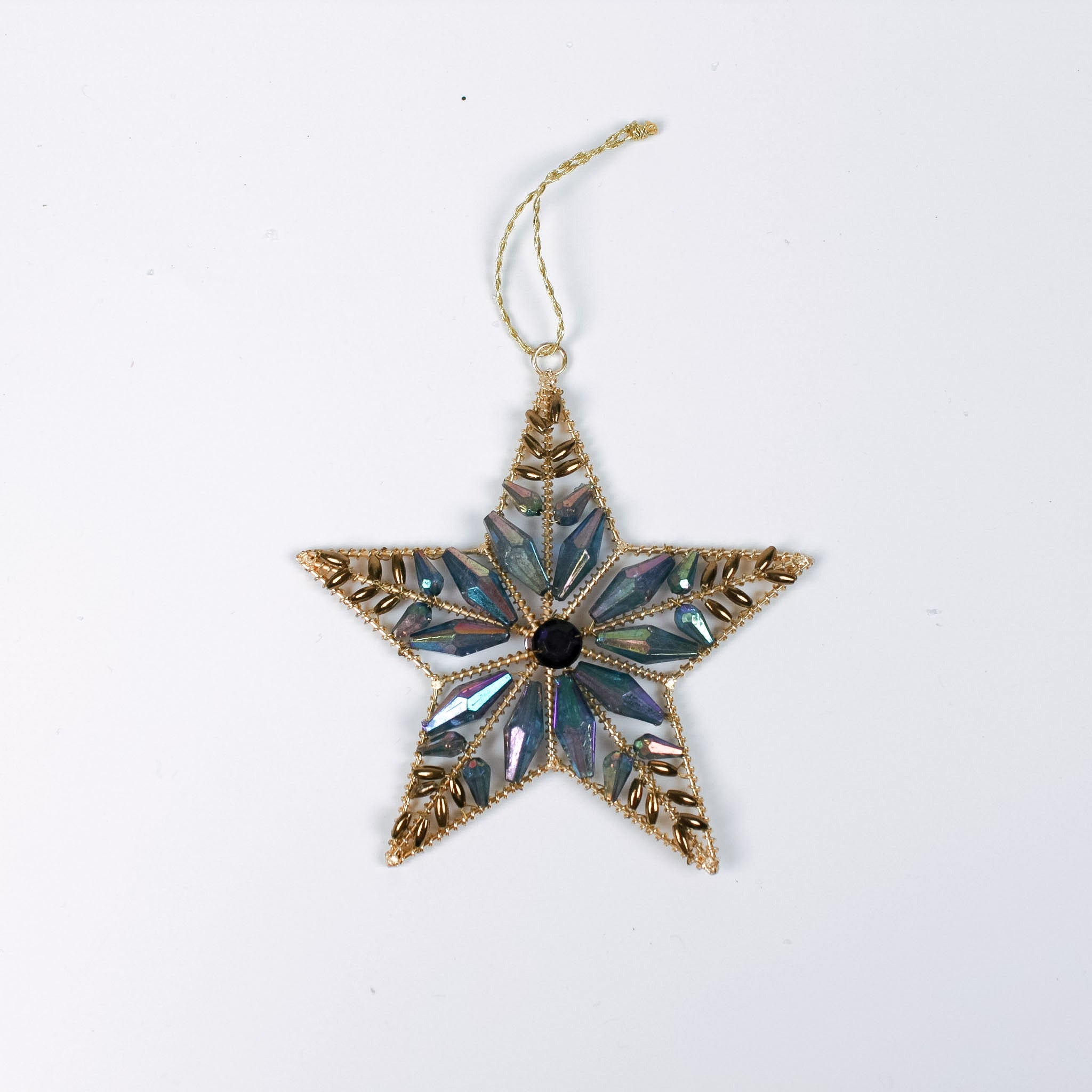 Gilt metal star shaped Christmas ornament decorated with blue and iridescent crystal accents and a dark gemstone at the center, displayed against a white background.