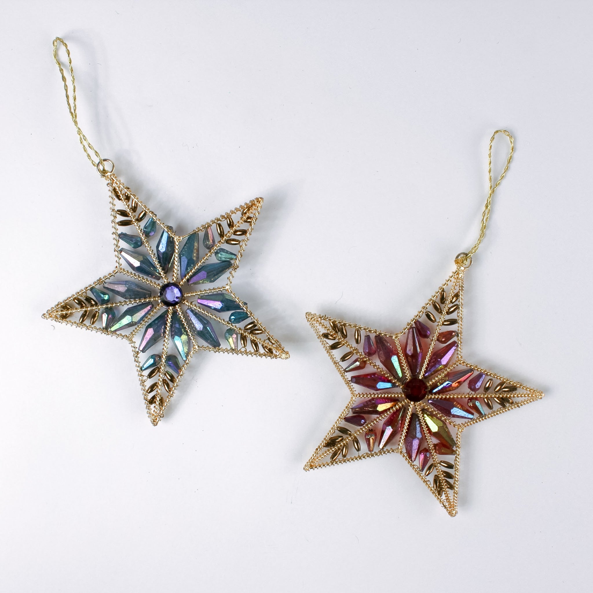 Two gilt metal star shaped Christmas ornaments decorated with colorful crystal accents