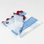 Folded white and blue striped cloth napkin with red scalloped edges, showing a corner flipped open to reveal the underside and a small brand tag.