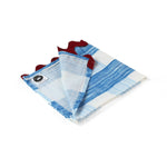 Folded white and blue gingham cloth napkin with red edges, showing a corner flipped open to reveal a small brand tag in a white background